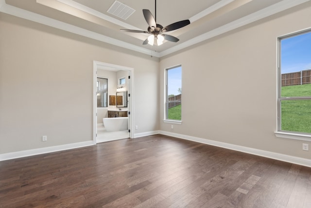 unfurnished room with dark wood-type flooring, a wealth of natural light, and a tray ceiling