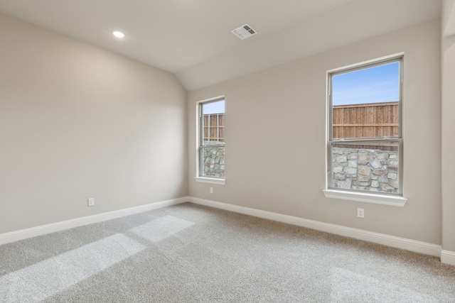 carpeted spare room featuring vaulted ceiling