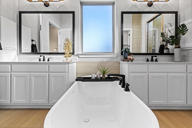 bathroom with a healthy amount of sunlight, wood-type flooring, and a tub