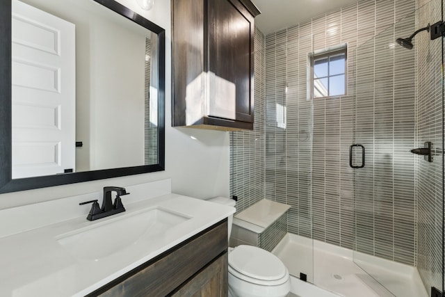 bathroom featuring a shower with shower door, vanity, and toilet