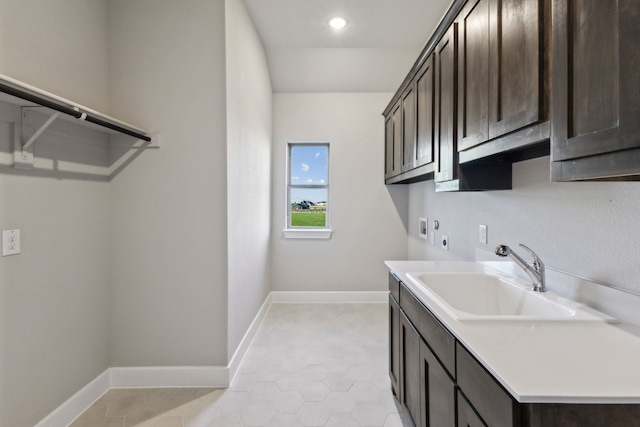 washroom with cabinets, electric dryer hookup, washer hookup, sink, and light tile patterned floors