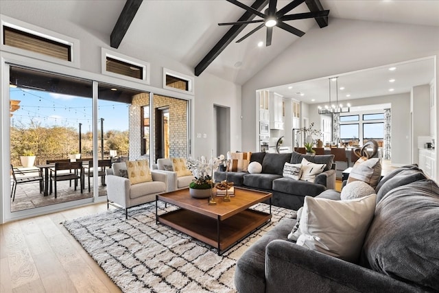 living room featuring beamed ceiling, ceiling fan with notable chandelier, high vaulted ceiling, and light hardwood / wood-style flooring