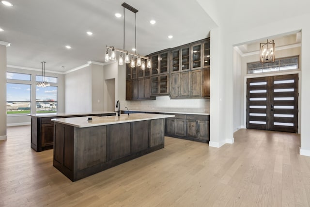 kitchen featuring dark brown cabinetry, light hardwood / wood-style flooring, a chandelier, and an island with sink