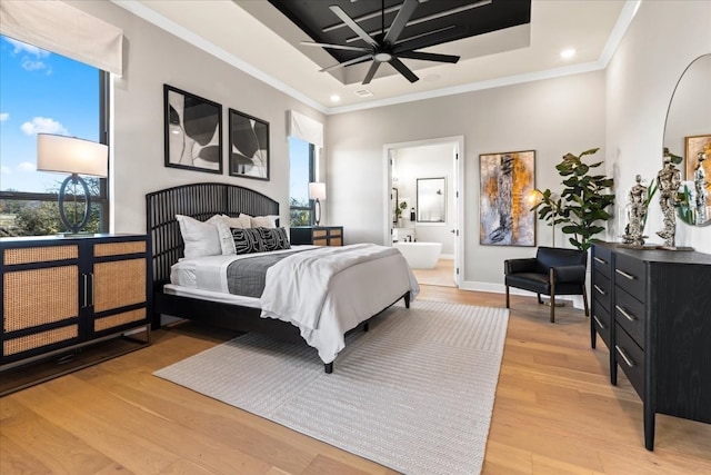 bedroom featuring hardwood / wood-style flooring, ensuite bath, a tray ceiling, and crown molding