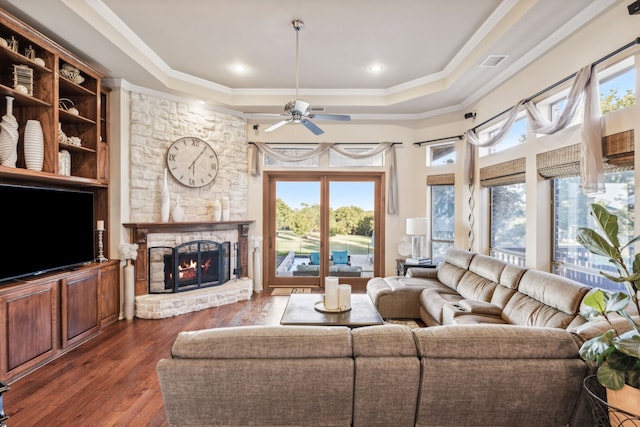 living room with a stone fireplace, crown molding, plenty of natural light, and dark hardwood / wood-style floors