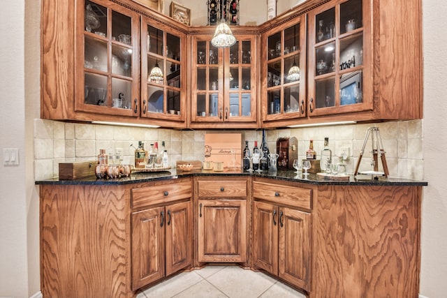 bar featuring light tile patterned flooring, backsplash, and dark stone countertops