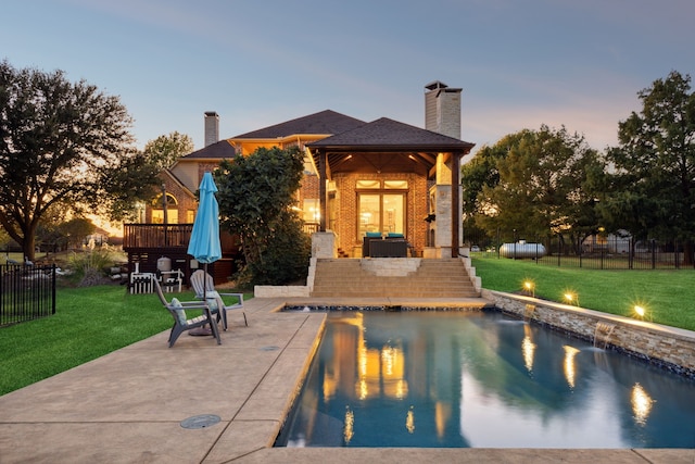 pool at dusk with a yard and a patio