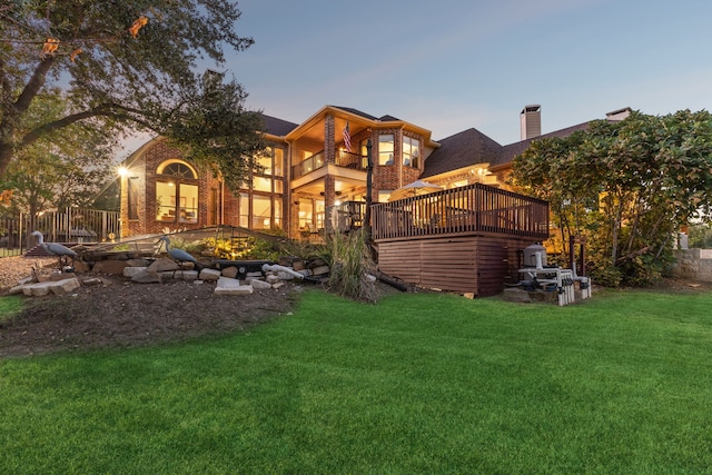 back house at dusk with a balcony and a yard