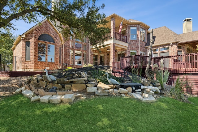 rear view of house featuring a lawn, a balcony, and a wooden deck