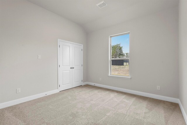 empty room featuring light carpet and vaulted ceiling