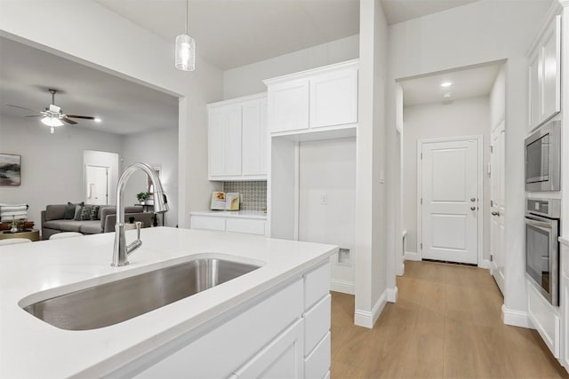 kitchen with white cabinets, decorative light fixtures, sink, and stainless steel appliances