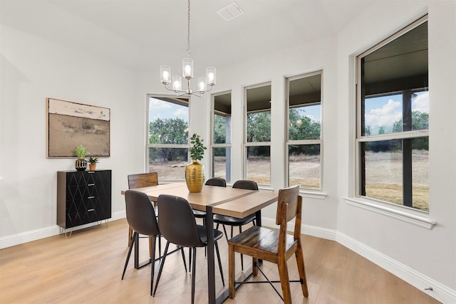 dining room featuring a notable chandelier, plenty of natural light, and light wood-type flooring