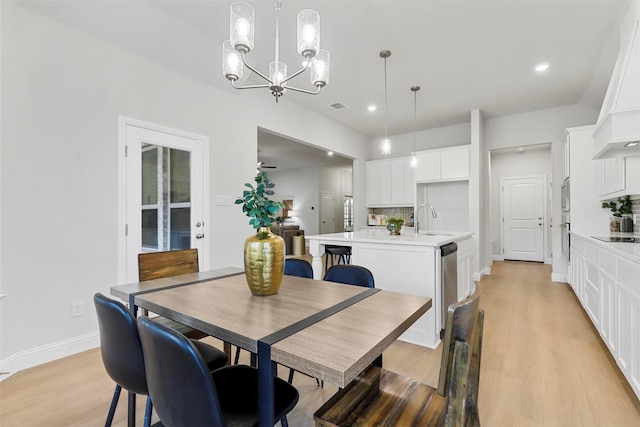 dining area with sink, a chandelier, and light hardwood / wood-style flooring