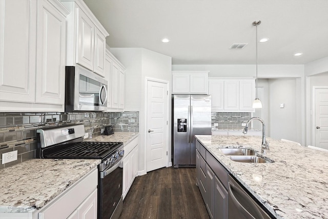 kitchen featuring appliances with stainless steel finishes, white cabinetry, dark hardwood / wood-style flooring, sink, and hanging light fixtures