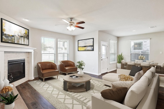 living room with dark wood-type flooring, ceiling fan, and a fireplace