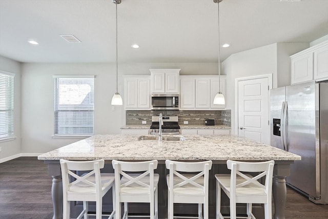 kitchen with tasteful backsplash, stainless steel appliances, white cabinets, a sink, and visible vents