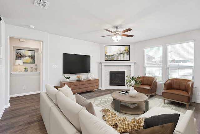 living room with visible vents, a glass covered fireplace, wood finished floors, baseboards, and ceiling fan