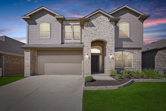 french country style house with a garage, brick siding, concrete driveway, and a lawn