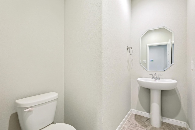 half bathroom featuring a sink, baseboards, and toilet