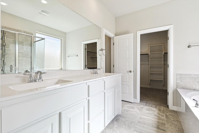 bathroom featuring a sink, visible vents, a walk in closet, and a stall shower