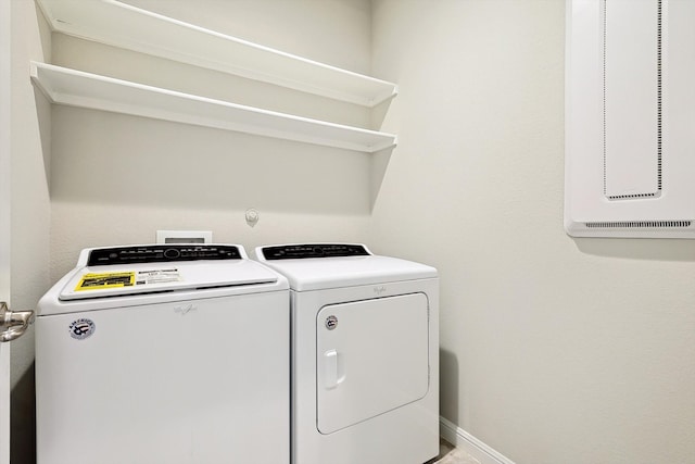 clothes washing area with laundry area, baseboards, and washer and clothes dryer