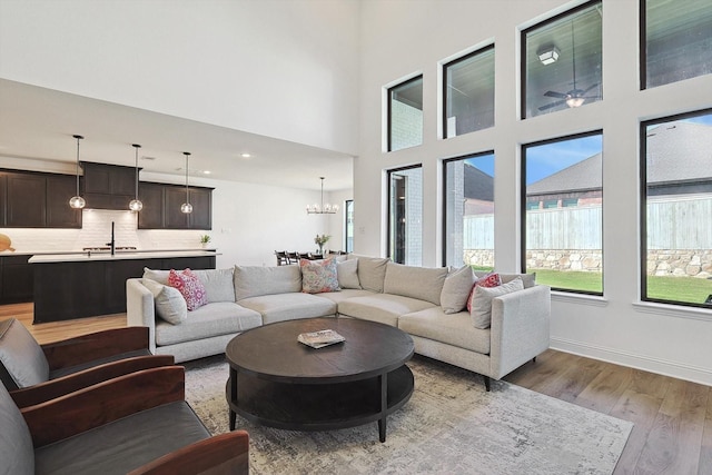 living room with a high ceiling, light hardwood / wood-style flooring, and a notable chandelier