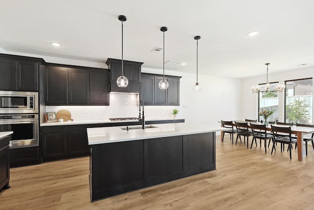 kitchen featuring hanging light fixtures, sink, appliances with stainless steel finishes, and an island with sink