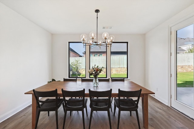 dining space with hardwood / wood-style flooring and a notable chandelier