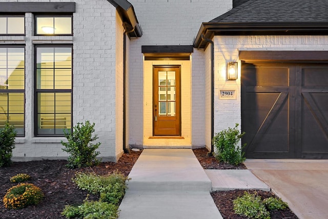 entrance to property with a garage and roof with shingles