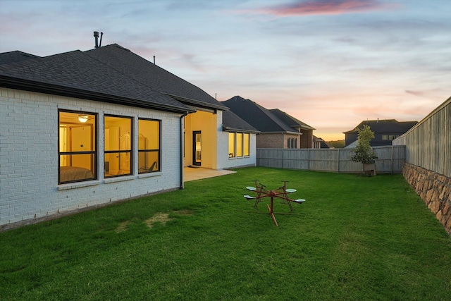 back house at dusk featuring a yard