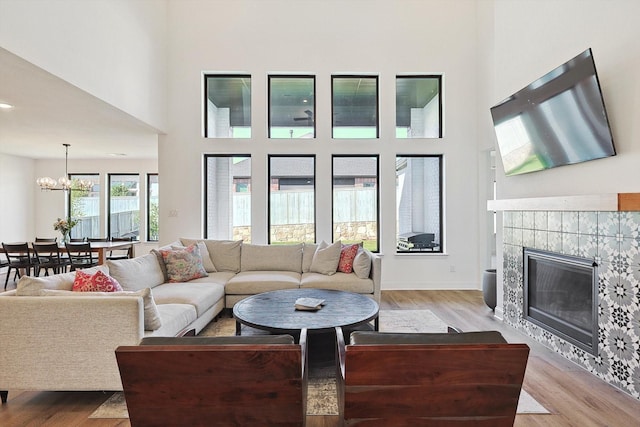 living room featuring a tiled fireplace, an inviting chandelier, and light hardwood / wood-style floors