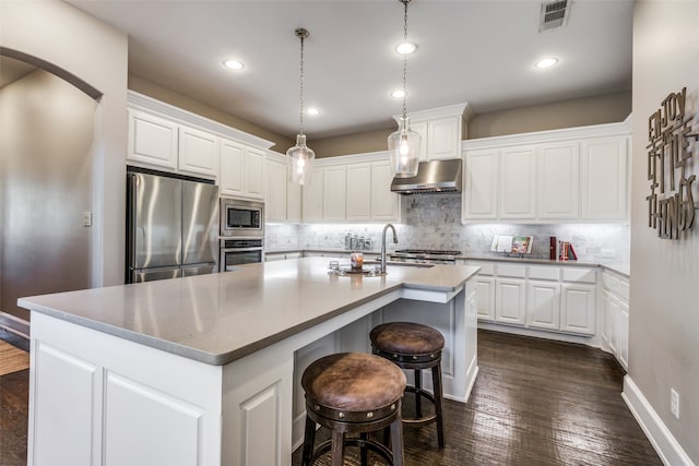 kitchen featuring white cabinetry, exhaust hood, and appliances with stainless steel finishes