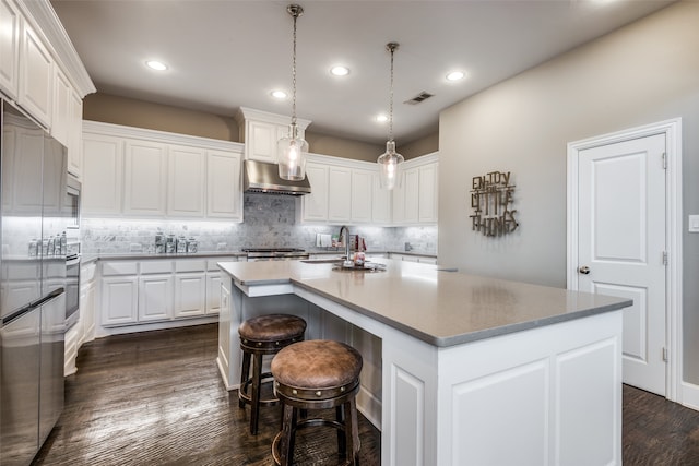 kitchen with a center island with sink, white cabinets, extractor fan, and decorative light fixtures