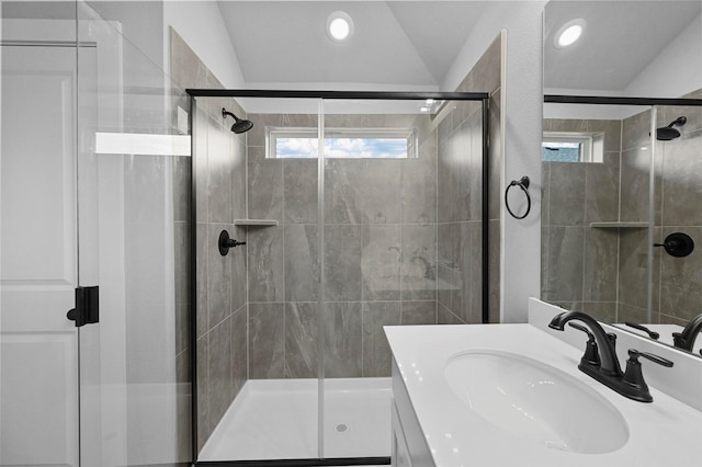 bathroom with walk in shower, vanity, a healthy amount of sunlight, and vaulted ceiling