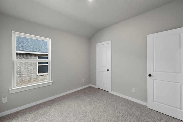 spare room with a healthy amount of sunlight, lofted ceiling, and carpet floors