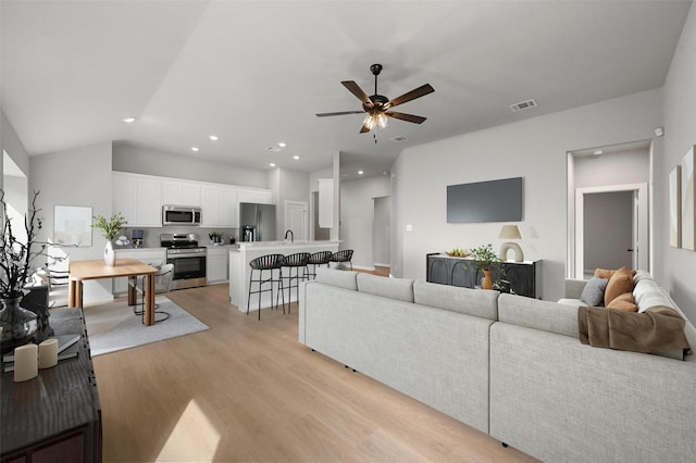 living room with ceiling fan, sink, light hardwood / wood-style flooring, and lofted ceiling