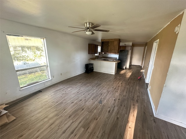 unfurnished living room with ceiling fan, sink, and dark wood-type flooring