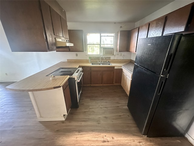 kitchen featuring sink, range with electric stovetop, a breakfast bar area, light wood-type flooring, and black refrigerator