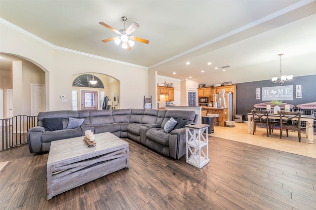 living room featuring ceiling fan with notable chandelier, ornamental molding, and dark wood-type flooring