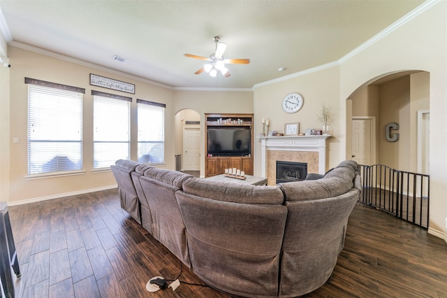 living room featuring ceiling fan, dark hardwood / wood-style floors, crown molding, and a tile fireplace