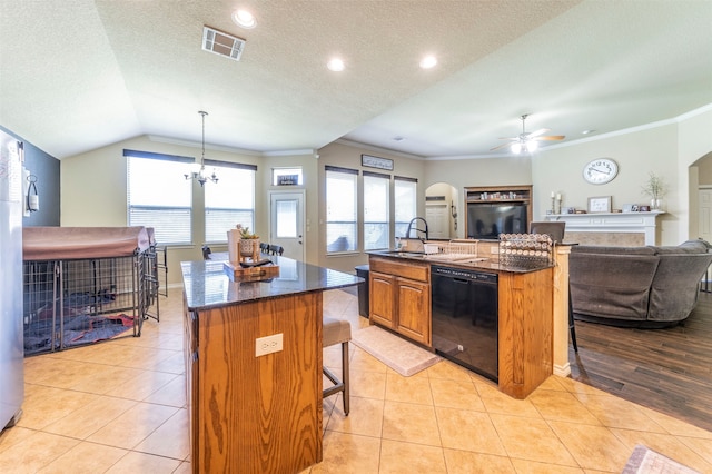 kitchen featuring pendant lighting, black dishwasher, a kitchen island with sink, ceiling fan with notable chandelier, and a kitchen bar