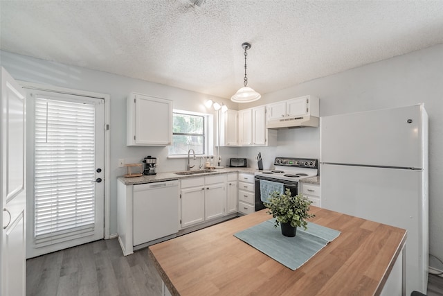 kitchen with hanging light fixtures, sink, white appliances, and white cabinetry