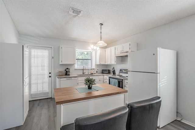 kitchen with sink, white appliances, light hardwood / wood-style flooring, decorative light fixtures, and white cabinetry