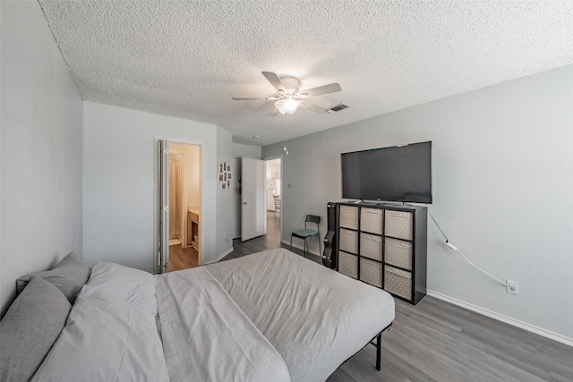 bedroom featuring ceiling fan, ensuite bathroom, hardwood / wood-style floors, and a textured ceiling