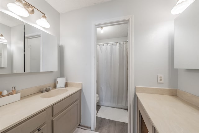 bathroom featuring a textured ceiling, hardwood / wood-style flooring, vanity, and toilet