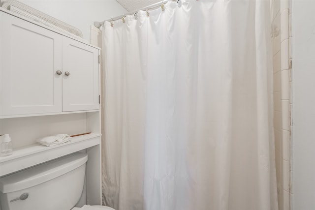 bathroom featuring a shower with shower curtain and toilet