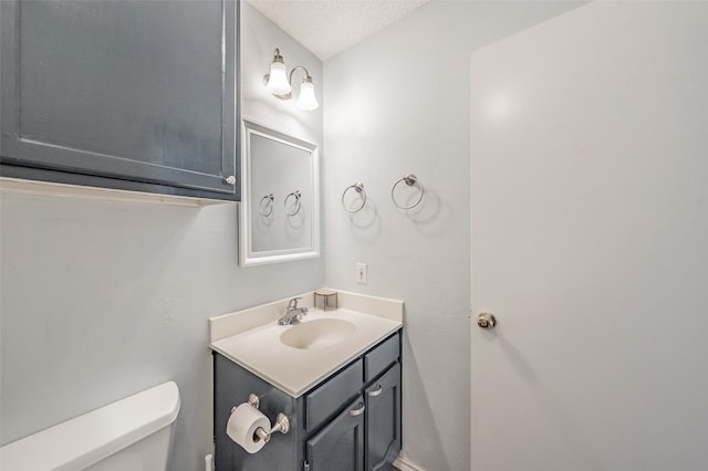 bathroom with a textured ceiling, vanity, and toilet