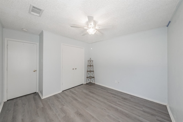 unfurnished bedroom with ceiling fan, a textured ceiling, a closet, and light hardwood / wood-style floors