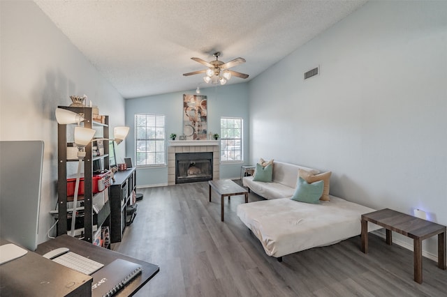 living room featuring a fireplace, a textured ceiling, wood-type flooring, lofted ceiling, and ceiling fan