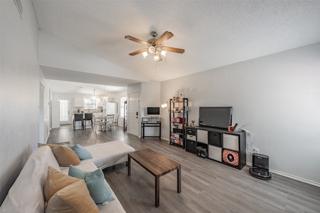 living room featuring ceiling fan with notable chandelier, lofted ceiling, a textured ceiling, and hardwood / wood-style flooring